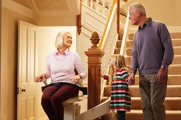 family looking at grandma on stairlift inside of home